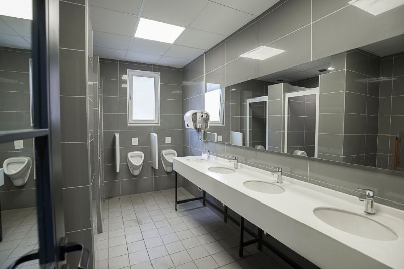 commercial bathroom with 3 sink and toilet for men