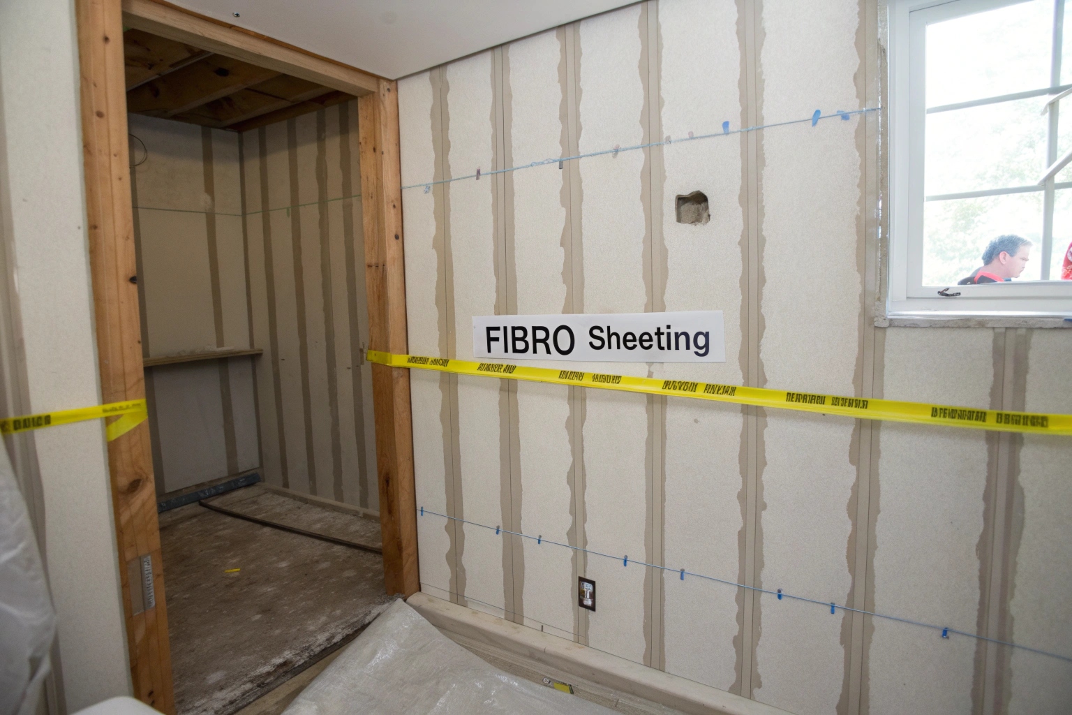 Exposed fibro sheeting in a stripped-back bathroom wall