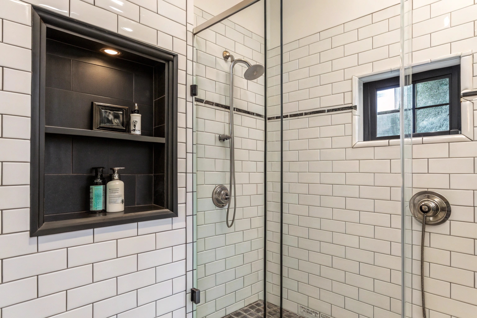 Finished shower renovation with white subway tiles and a dark feature niche